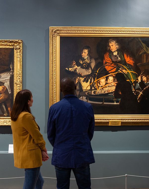 A couple looking at a Joseph Wright painting