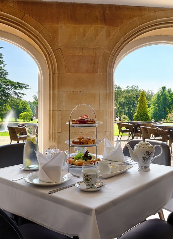 A table set for Afternoon Tea, looking out over beautiful green grounds.