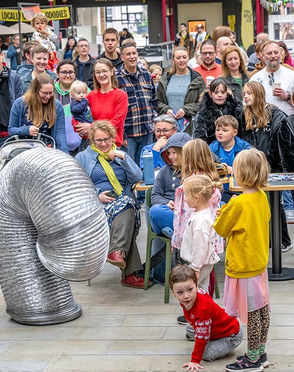 A large crowd of adults and children gathered around a shiny metal tube at Derby Feste