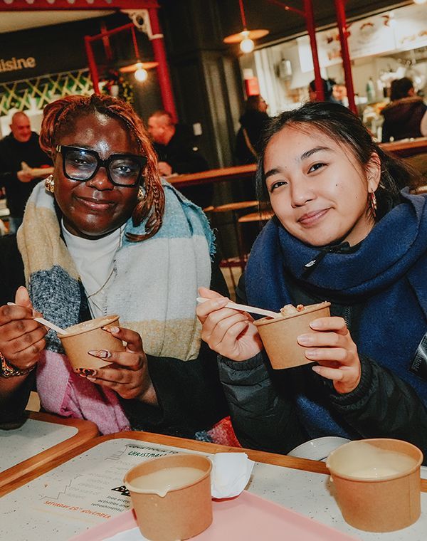 Two women enjoying crumble at Derby Market Hall