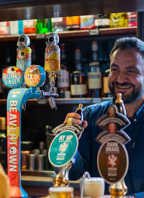 Smiling barman pulling a pint in the Exeter Arms