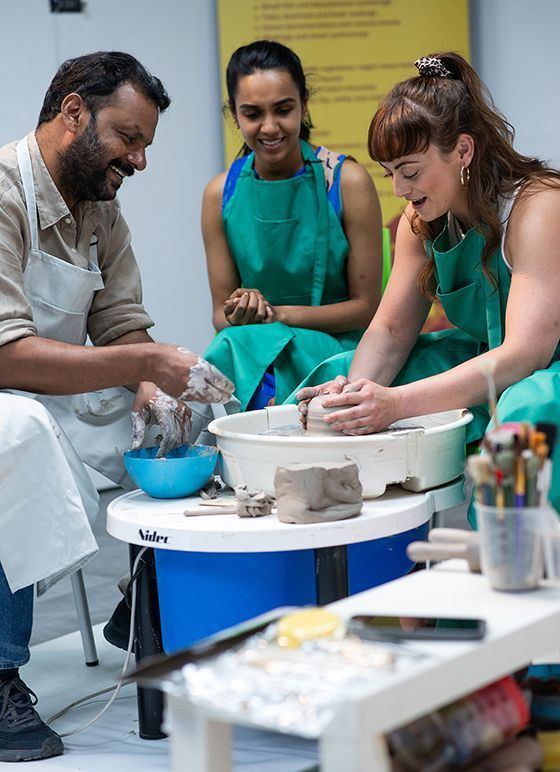 Three people taking part in a pottery class